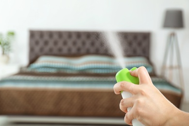 Photo of Woman spraying air freshener in bedroom