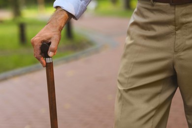 Photo of Senior man with walking cane outdoors, closeup