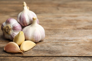 Photo of Fresh organic garlic on wooden table. Space for text