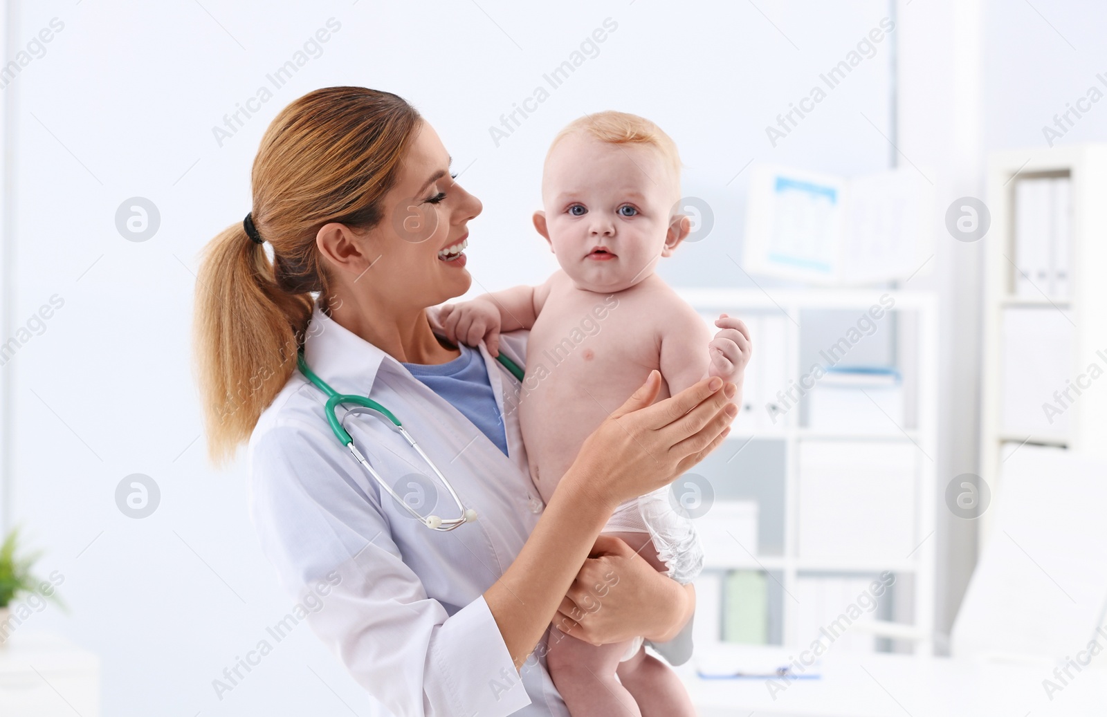 Photo of Children's doctor with cute baby in hospital. Space for text