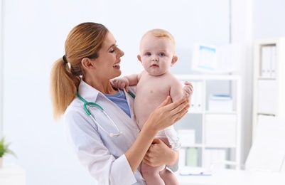 Photo of Children's doctor with cute baby in hospital. Space for text