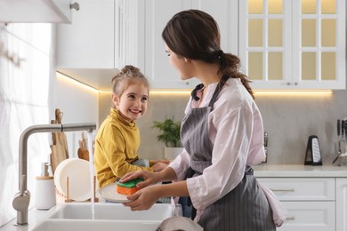 Photo of Young mother and her daughter spending time together in kitchen