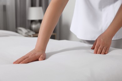 Photo of Maid making bed in hotel room, closeup