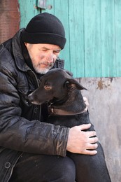 Poor homeless senior man with stray dog outdoors