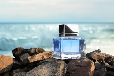 Image of Bottle of aquatic perfume on stones near ocean. Fresh sea breeze scent