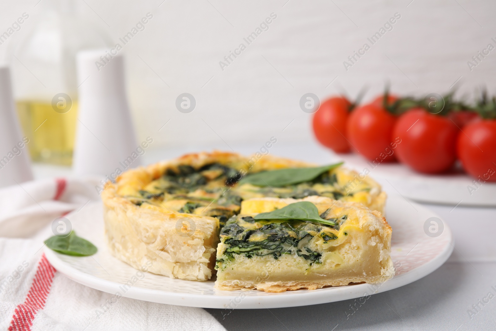 Photo of Delicious pie with spinach on white tiled table