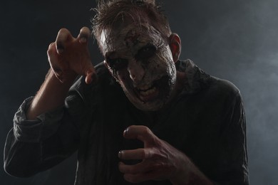 Photo of Scary zombie on dark background. Halloween monster