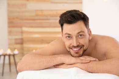 Handsome man relaxing on massage table in spa salon