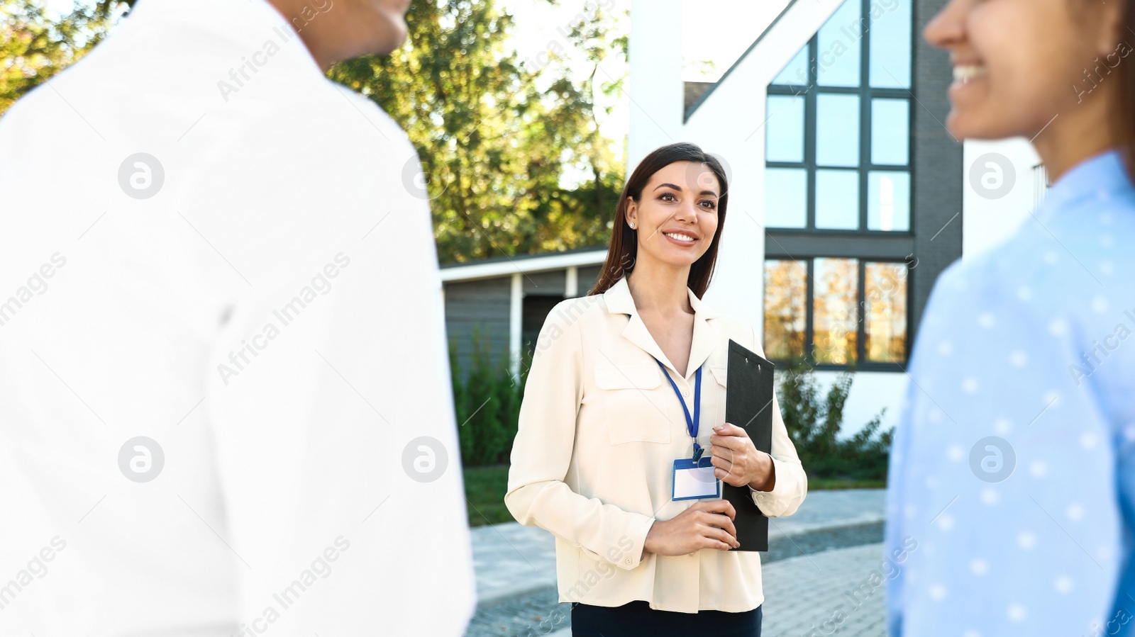 Photo of Real estate agent showing house to young couple outdoors