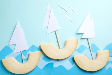 Photo of Composition with sailboats made of melon slices on light blue background, flat lay