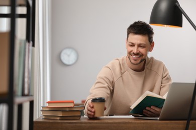 Happy man with cup of coffee studying in library