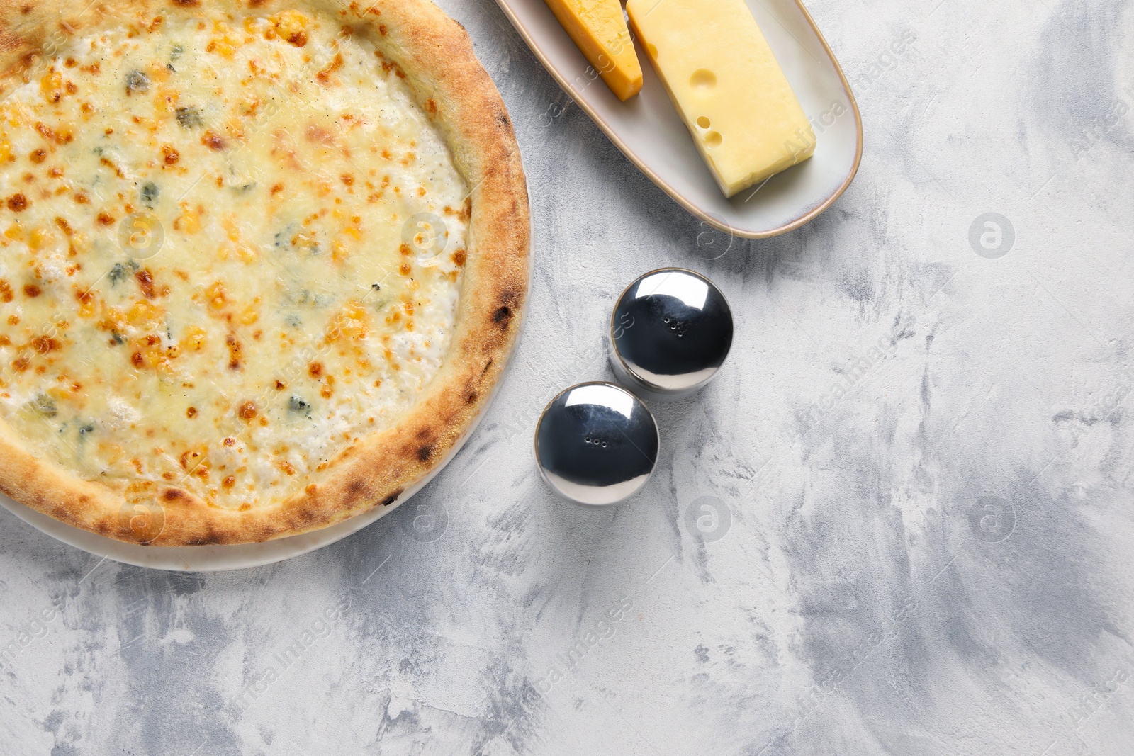 Photo of Delicious cheese pizza and different kinds of cheese on light grey textured table, flat lay. Space for text