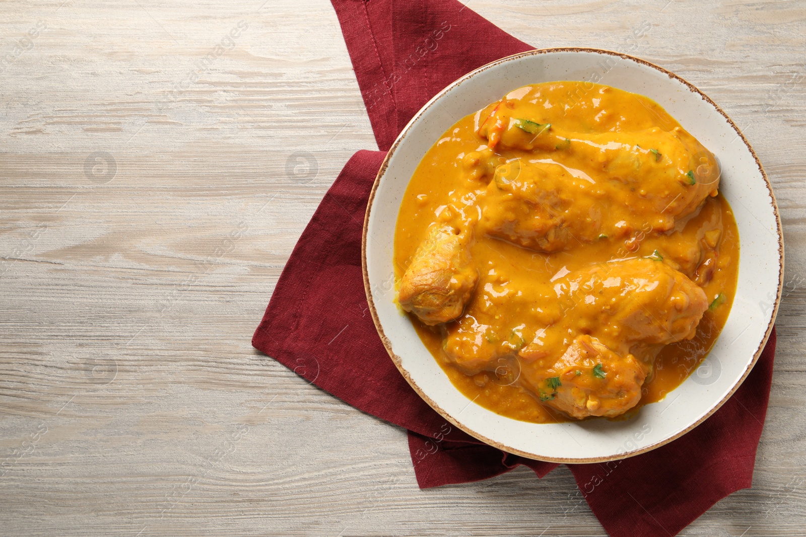 Photo of Tasty chicken curry on wooden table, top view. Space for text