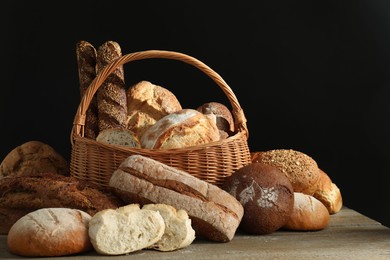 Photo of Wicker basket with different types of fresh bread on wooden table
