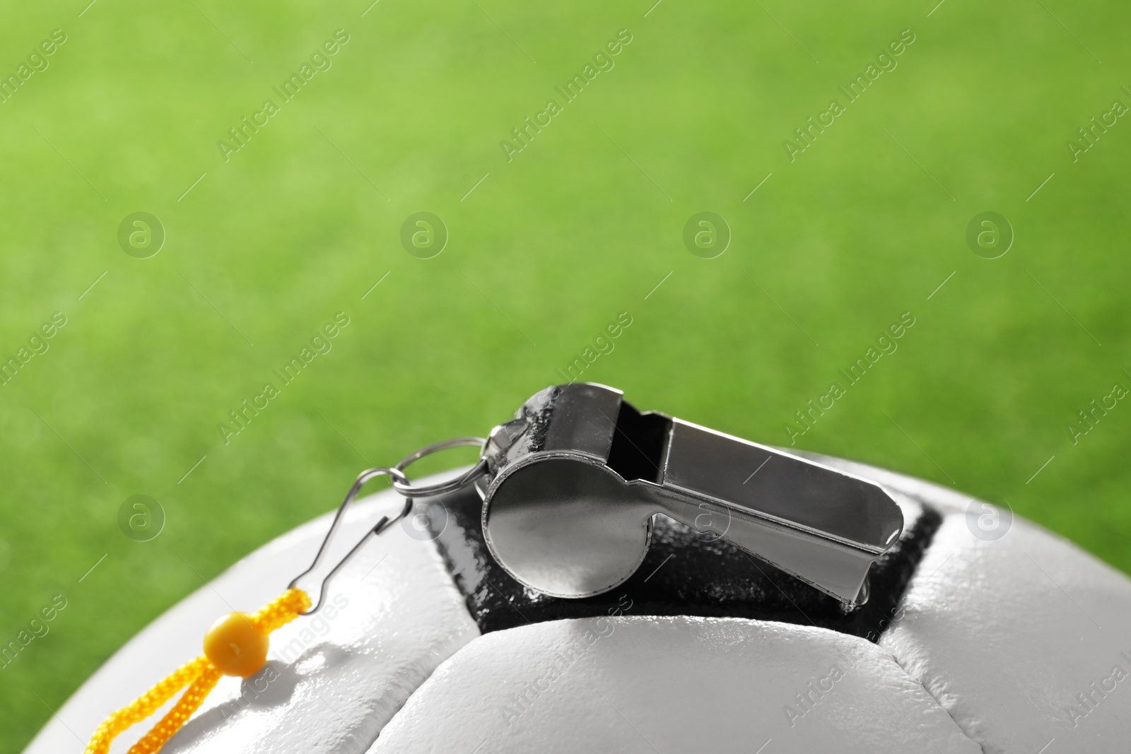 Photo of Football referee equipment. Soccer ball and metal whistle on green grass, closeup with space for text