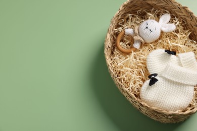 Photo of Different baby accessories in wicker box on green background, top view. Space for text