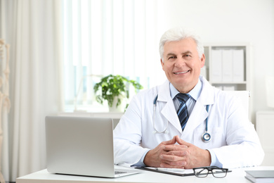 Portrait of senior doctor in white coat at workplace