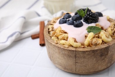 Tasty granola, yogurt and fresh berries in bowl on white tiled table, closeup with space for text. Healthy breakfast