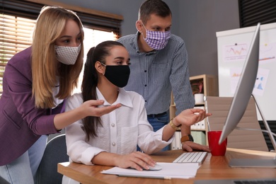 Coworkers with masks in office. Protective measure during COVID-19 pandemic