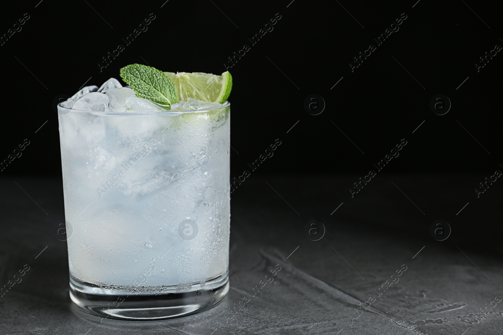 Photo of Cocktail with ice cubes, lime and mint on grey table, closeup. Space for text