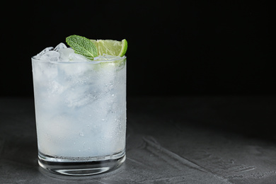 Cocktail with ice cubes, lime and mint on grey table, closeup. Space for text