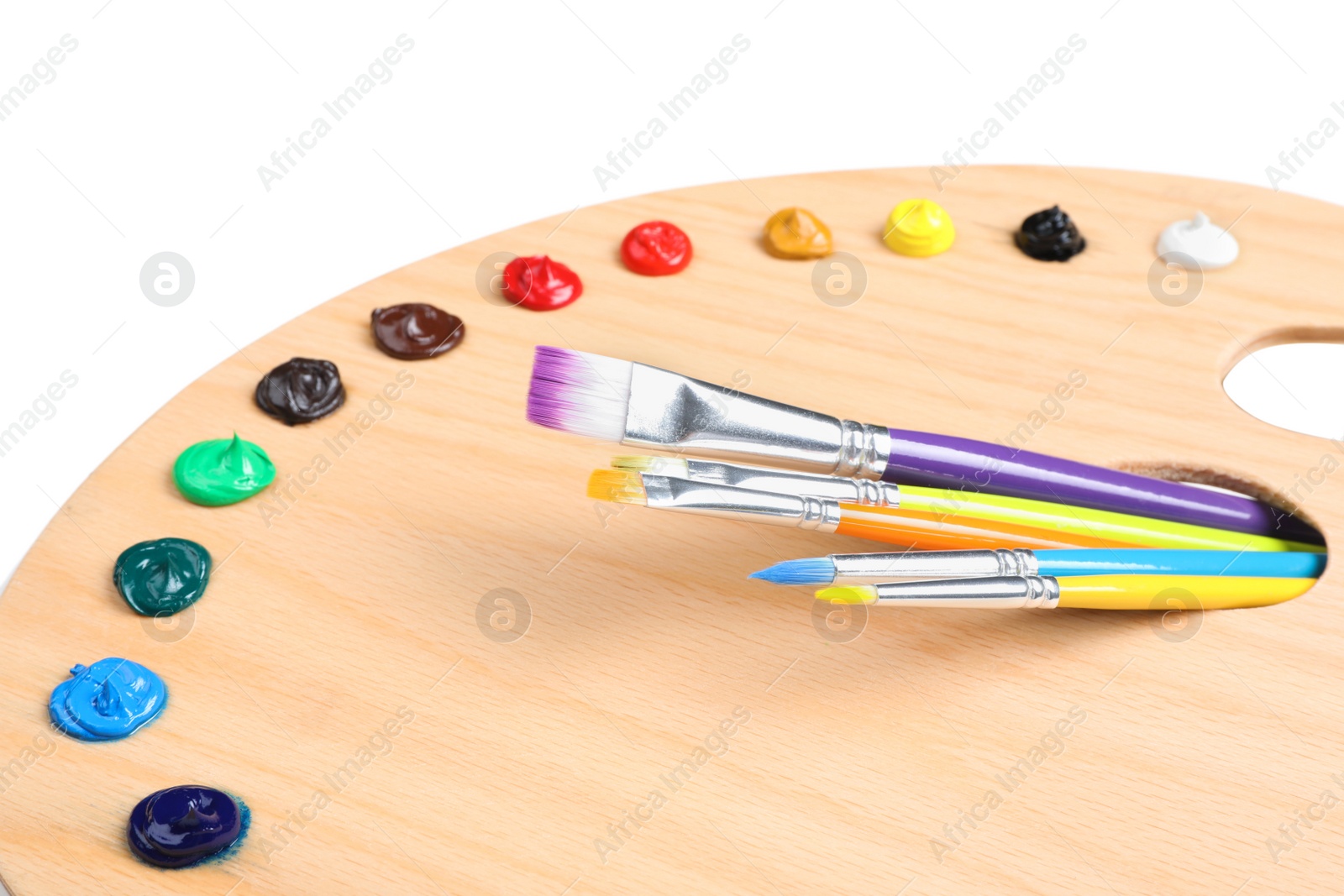 Photo of Palette with paints and brushes on white background, closeup. Artist equipment