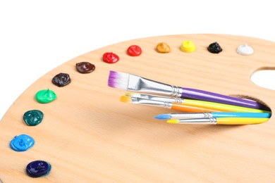 Photo of Palette with paints and brushes on white background, closeup. Artist equipment