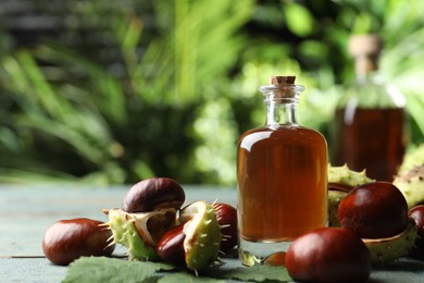 Photo of Chestnuts and bottle of essential oil on table against blurred background. Space for text