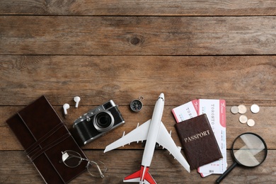 Flat lay composition with toy airplane and travel items on wooden background. Space for text