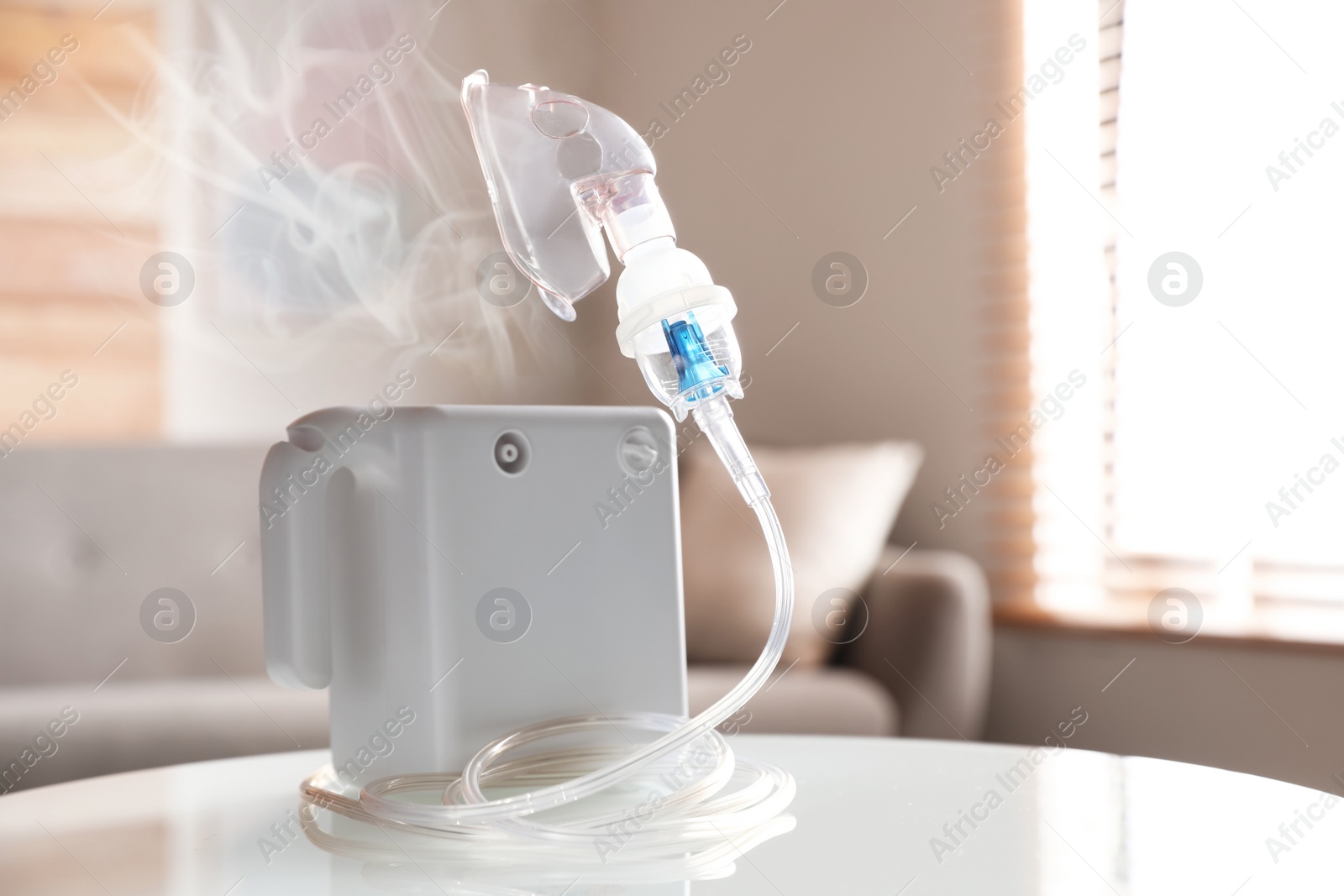 Image of Modern nebulizer with face mask on white table indoors. Inhalation equipment