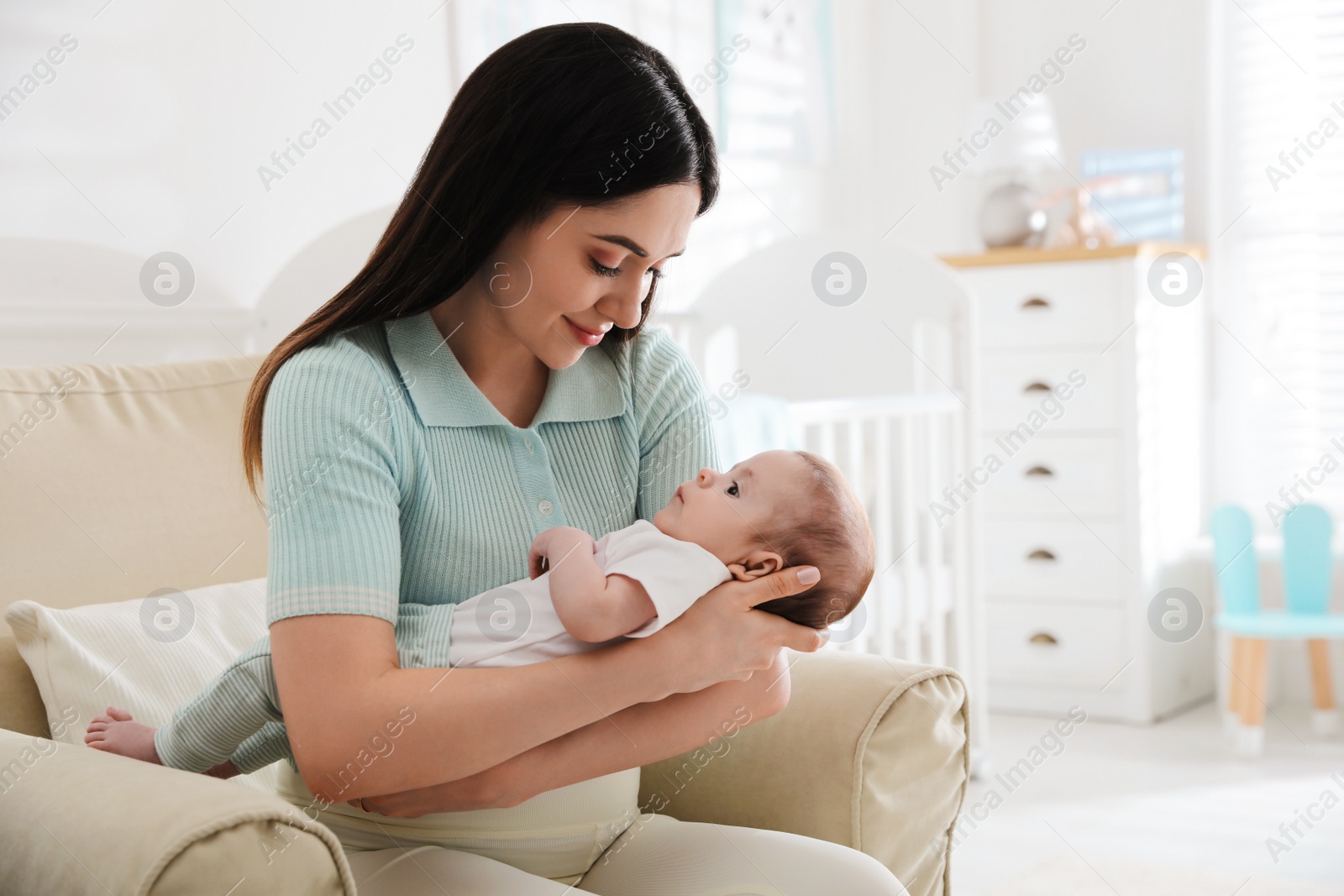 Photo of Young woman with her cute baby at home, space for text