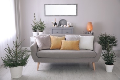 Photo of Beautiful room interior with decorated Christmas firs and comfortable sofa