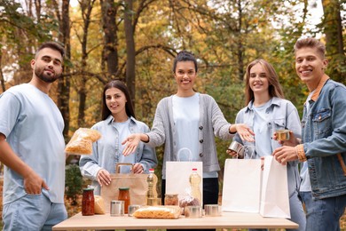 Photo of Portrait of volunteers packing food products at table in park