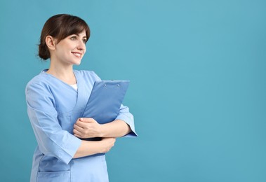 Photo of Portrait of smiling medical assistant with clipboard on light blue background. Space for text