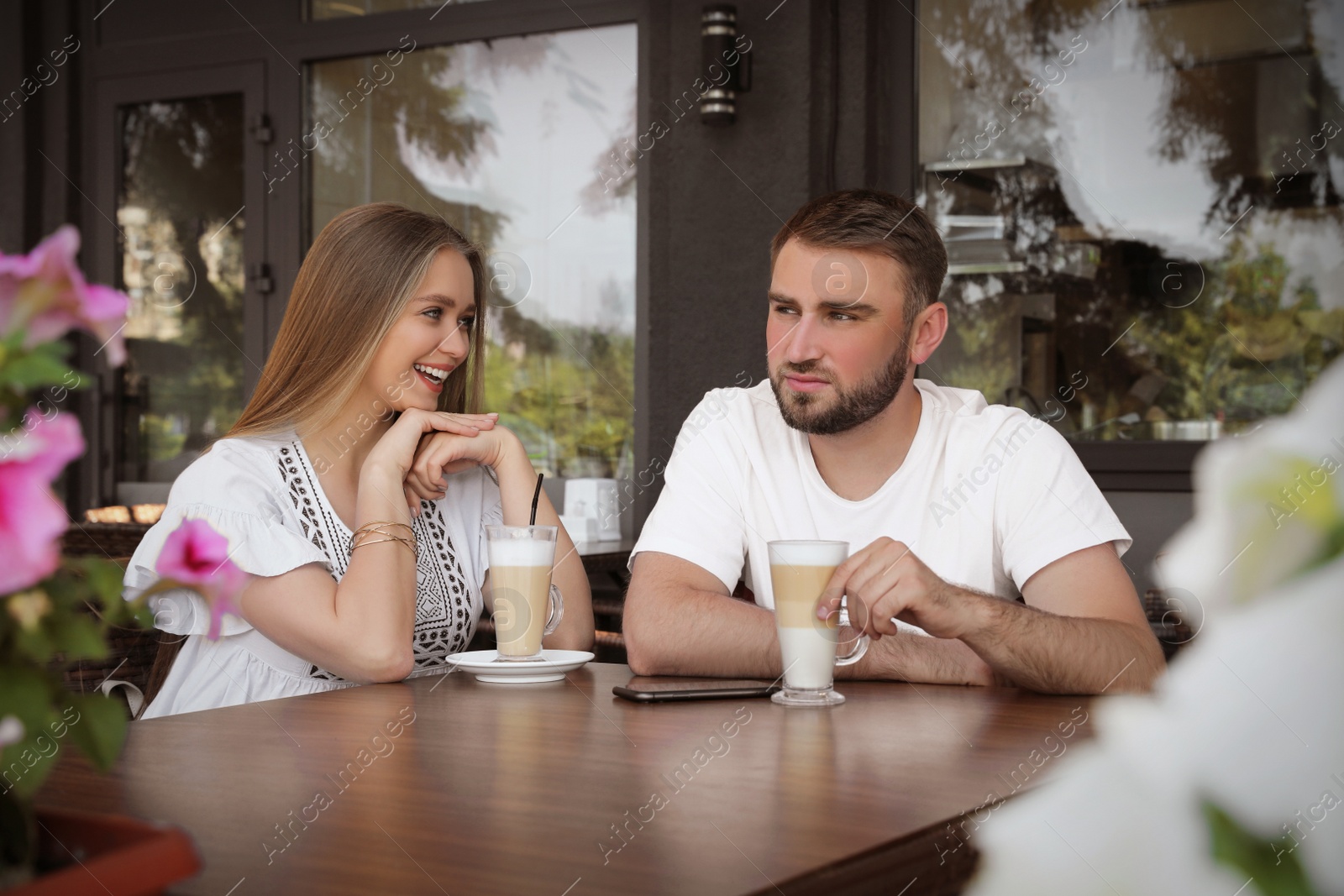 Photo of Young man having boring date with talkative girl in outdoor cafe