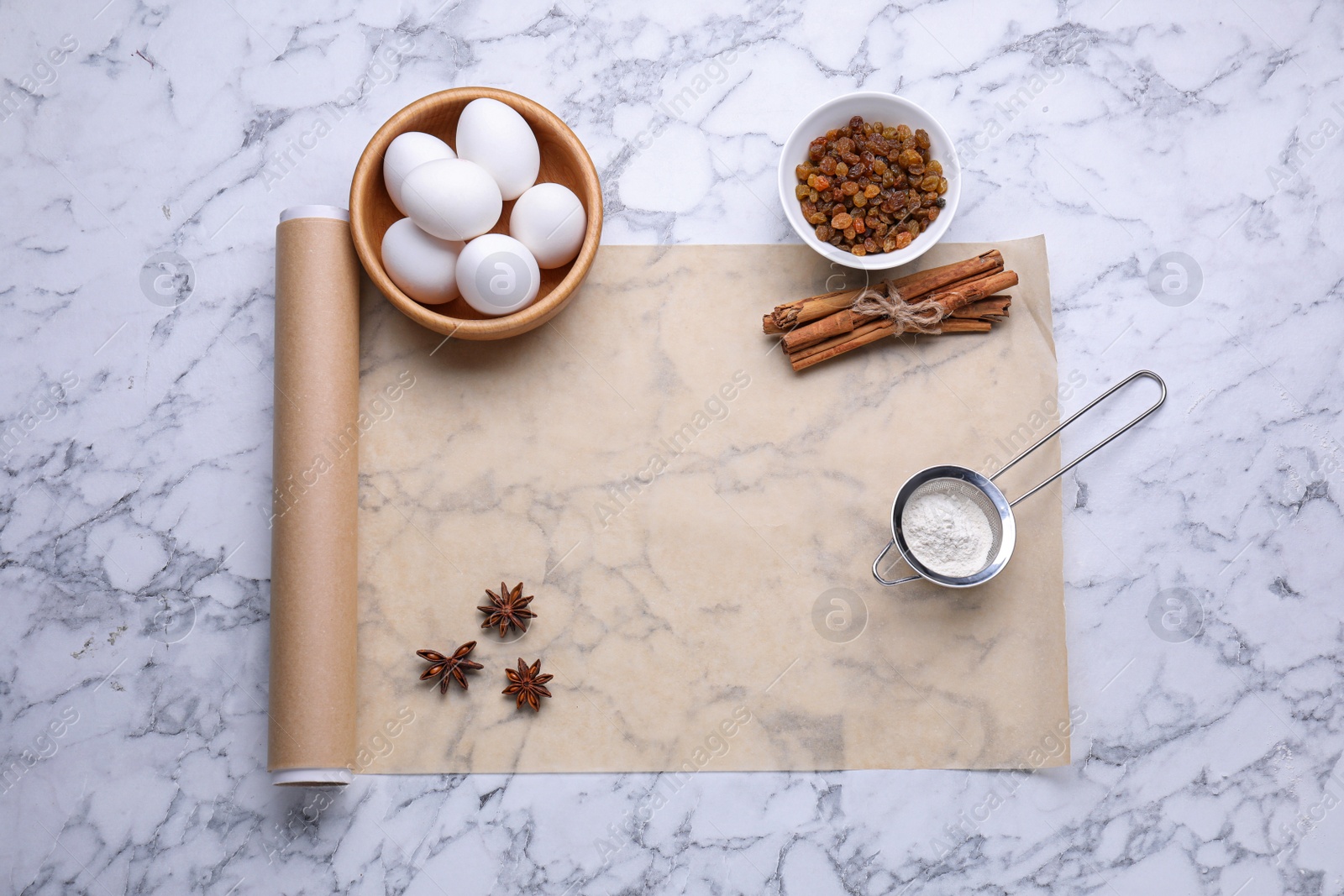 Photo of Roll of baking parchment paper and different ingredients on white marble table, flat lay. Space for text