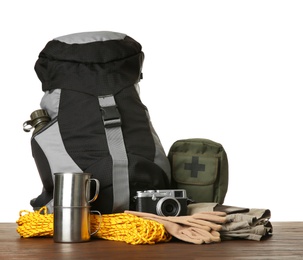 Set with different camping equipment on wooden table against white background