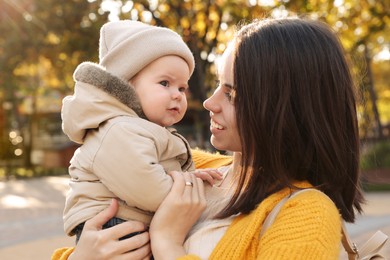 Happy mother with her baby son outdoors on autumn day