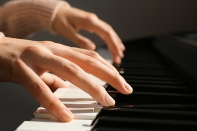 Photo of Young woman playing piano against grey background, closeup