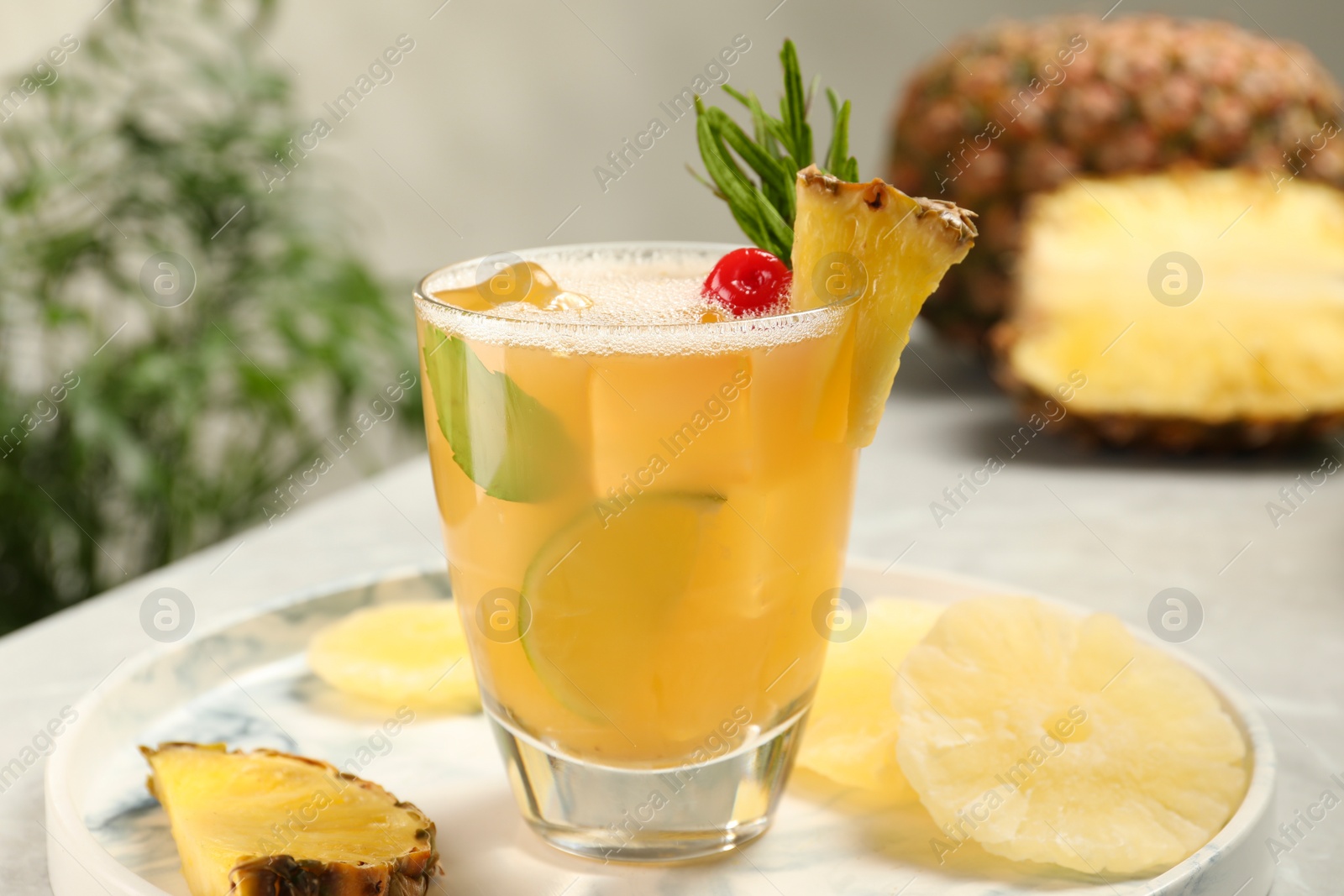 Photo of Glass of tasty pineapple cocktail and fresh fruit on light gray table, closeup