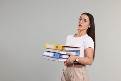 Frustrated woman with folders on light gray background, space for text