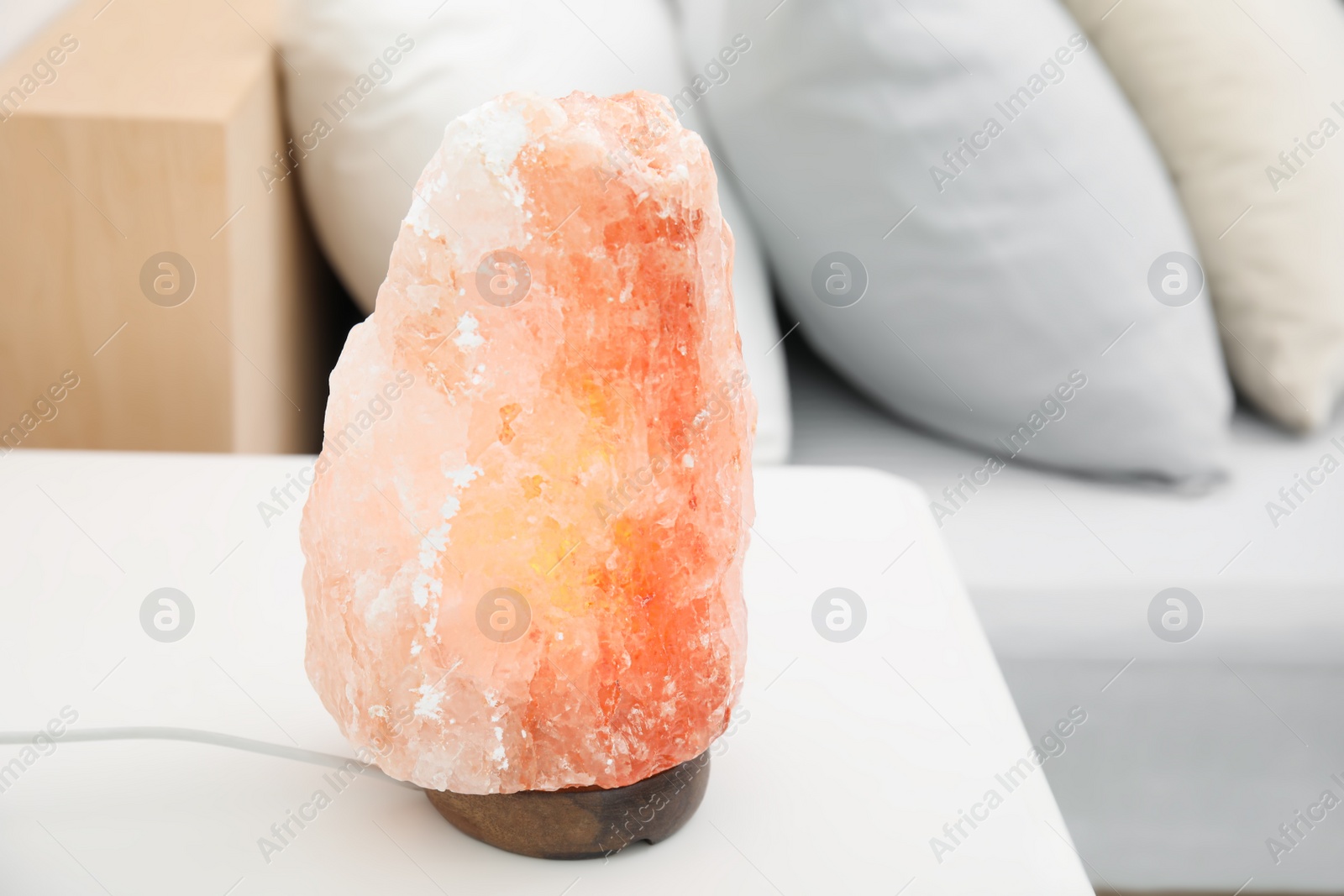 Photo of Himalayan salt lamp on white table in bedroom. Space for text