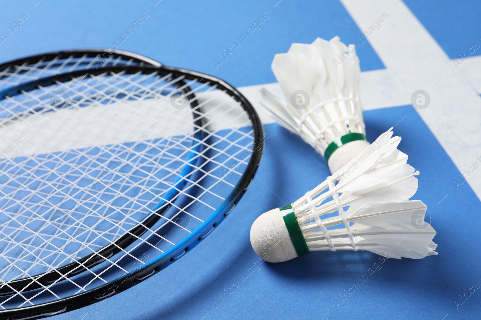 Photo of Feather badminton shuttlecocks and rackets on blue background, closeup