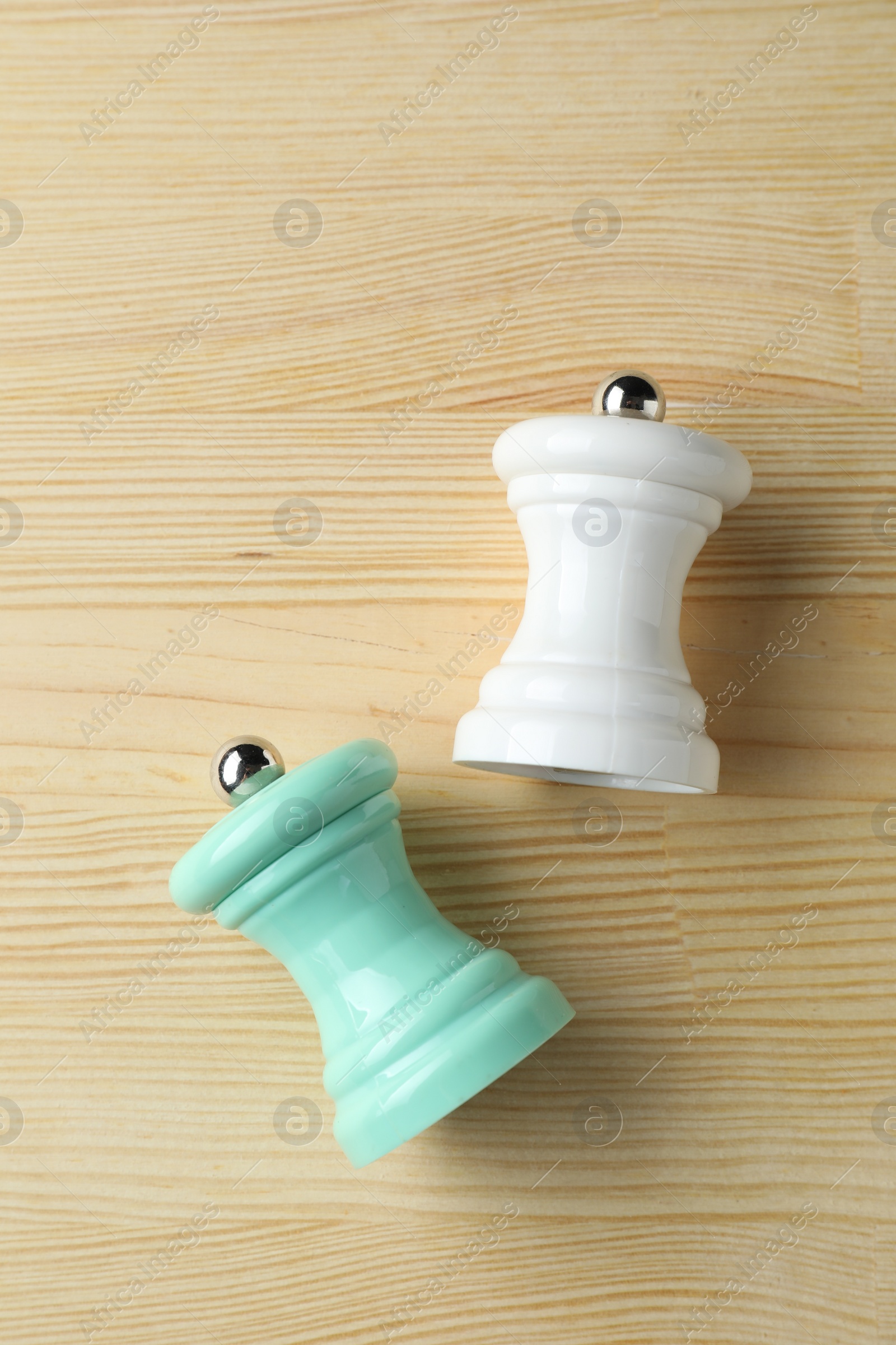 Photo of Salt and pepper shakers on light wooden table, top view