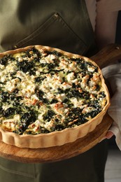 Photo of Woman holding delicious homemade spinach quiche, closeup