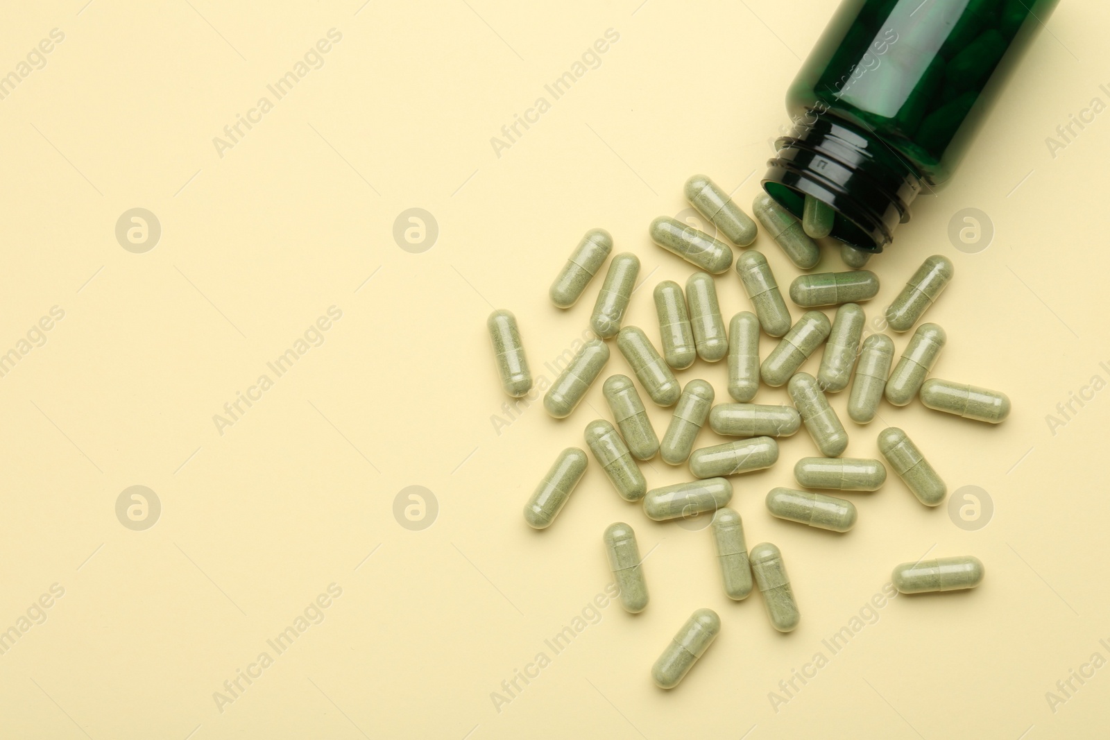 Photo of Vitamin pills and bottle on beige background, top view. Space for text