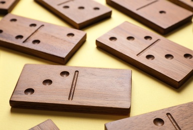 Photo of Wooden domino tiles on yellow background, closeup