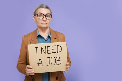 Photo of Unemployed senior woman holding cardboard sign with phrase I Need A Job on purple background. Space for text