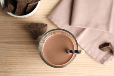 Photo of Flat lay composition with glass of tasty chocolate milk on wooden background. Dairy drink