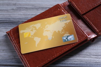 Photo of Credit card and leather wallet on grey wooden table
